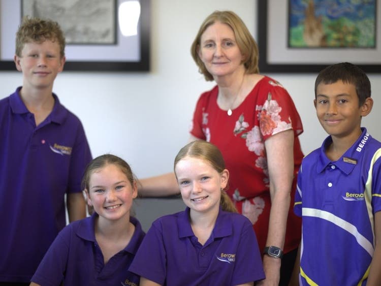 A group of two boys, two girls and the school principal, they are smiling.