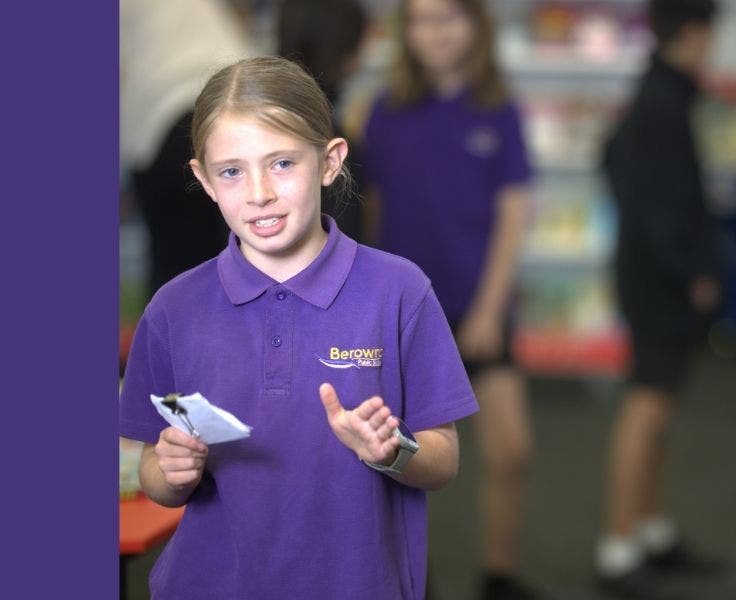 a girl in a purple shirt holding some palm cards speaking